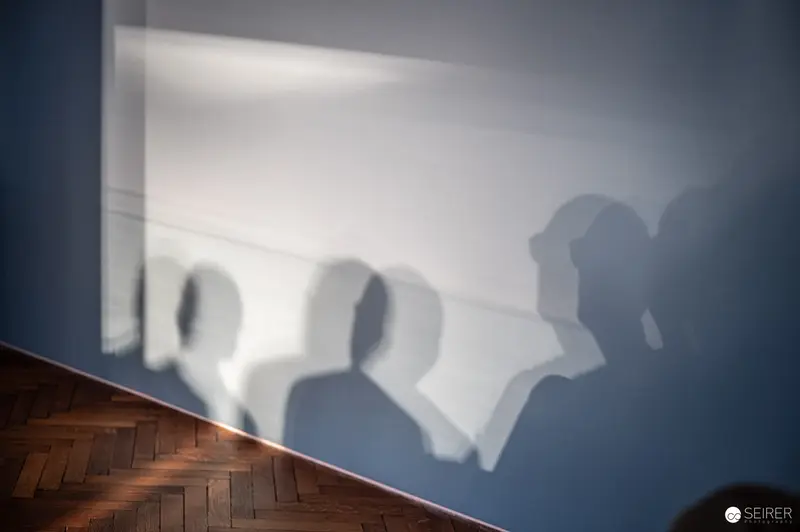 Blurred Silhouettes Casting Shadows on Wall with Wooden Floor