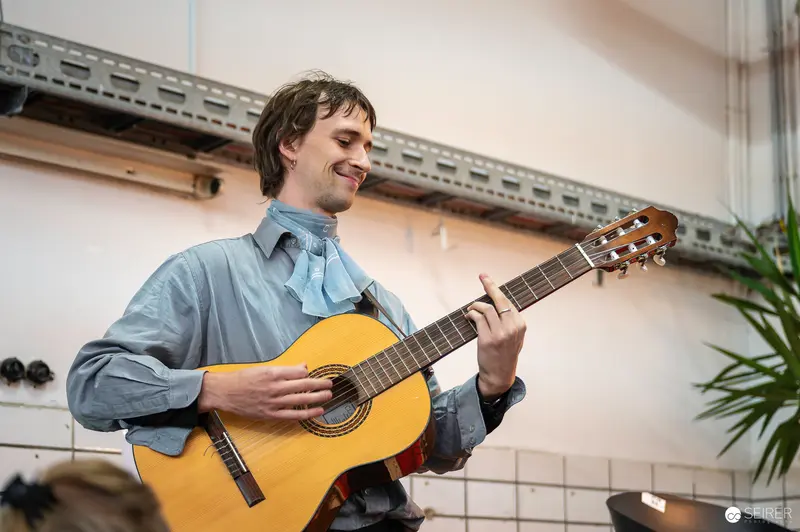 Smiling Musician Playing Yellow Acoustic Guitar in Indoor Setting