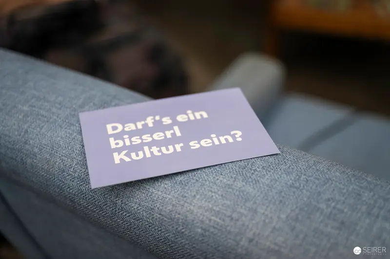 Reflective Postcard Questioning Cultural Identity on Gray Fabric Background