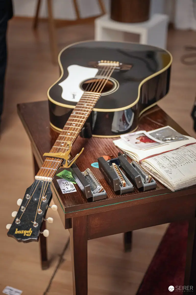 Vintage Acoustic Guitar with Harmonicas on Wooden Side Table