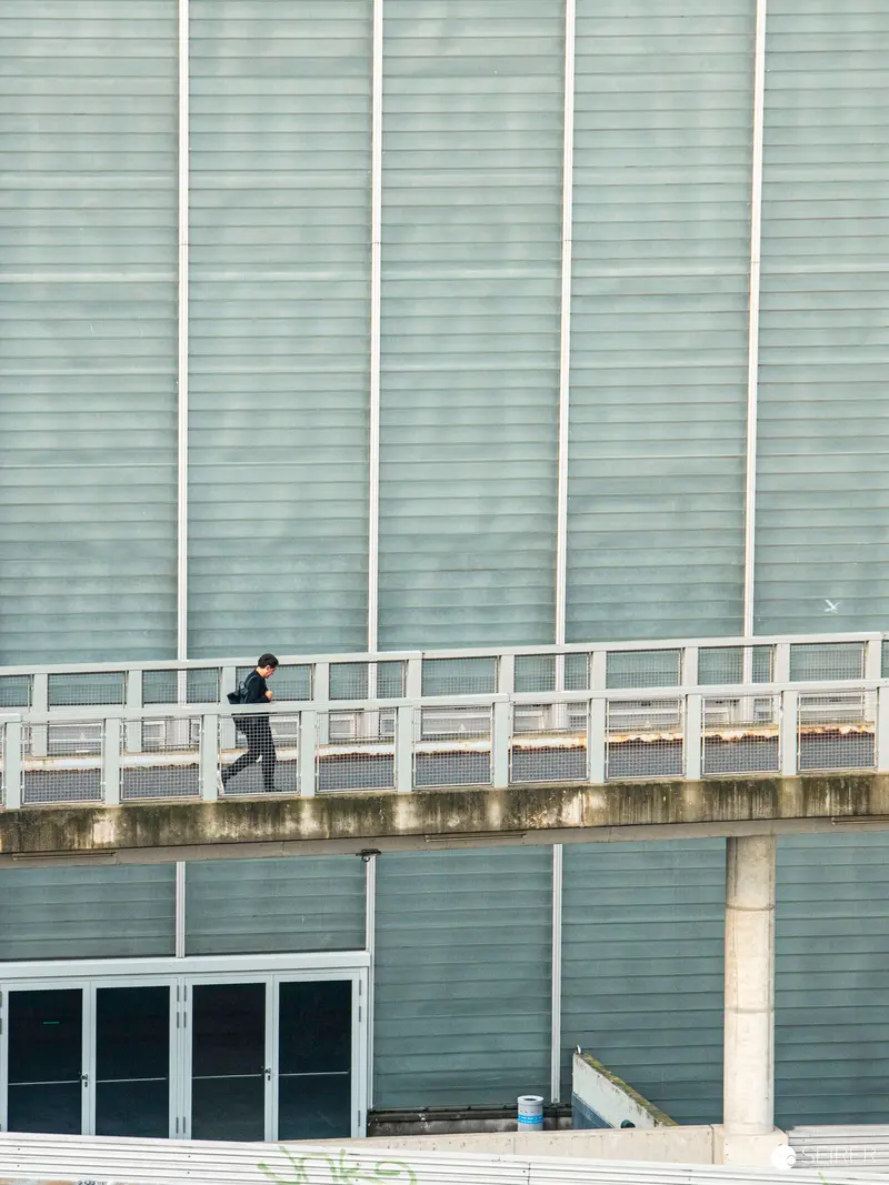 Lone Runner Crossing Elevated Walkway at Modern Urban Complex