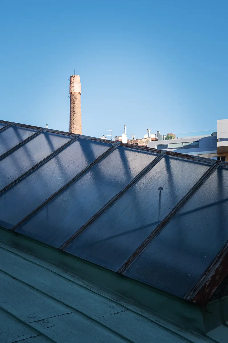Solar Panel Roof Array with Industrial Brick Chimney Against Blue Sky