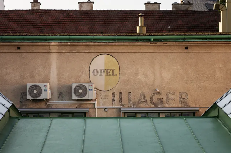 Faded Opel Sign on Vintage Building with Green Roof and Air Conditioners