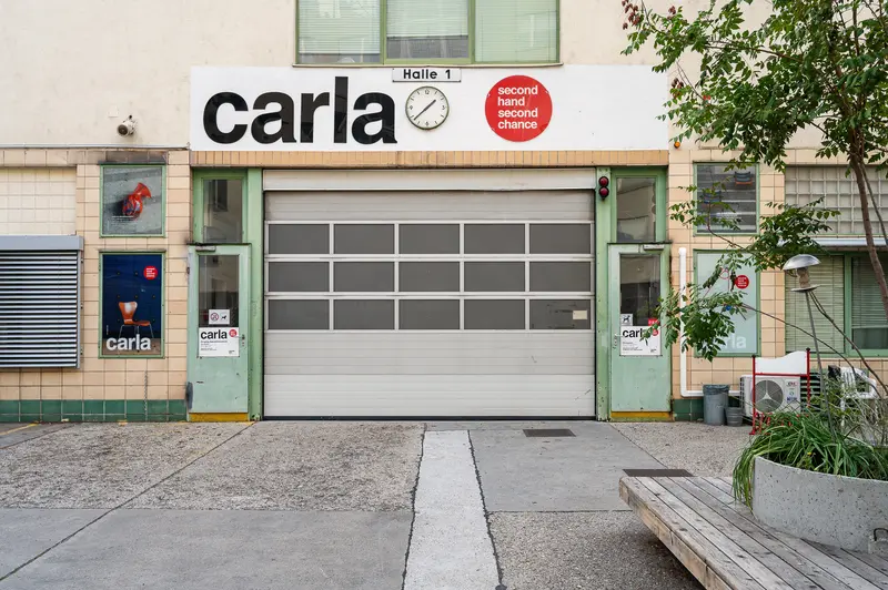 Carla Second-Hand Store Facade with Glass Garage Door in Urban Setting