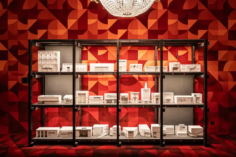 Architectural Model Exhibition: White Scale Models on Geometric Red Shelving