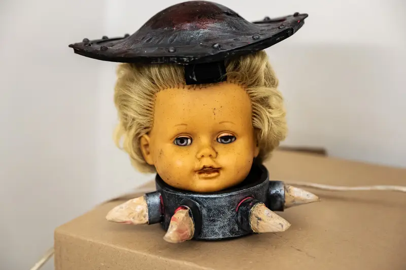 Vintage Doll Head with Leather Hat and Spiked Collar on Cardboard Box