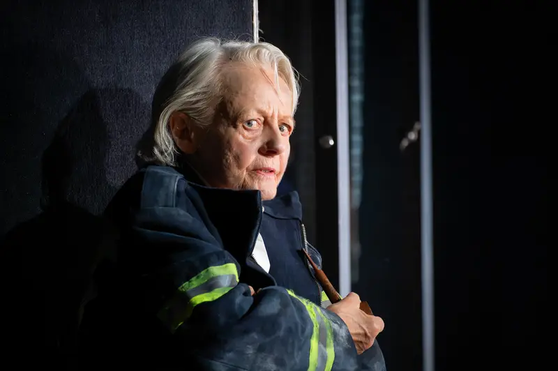Elderly Performer in Dark Theater Costume with Reflective Safety Vest