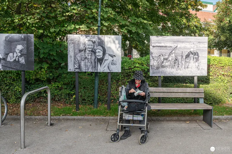 Elderly Person at Outdoor Photo Exhibition with Black and White Portraits