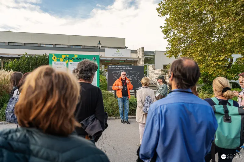 Lois Lammerhuber Leads La Gacilly Baden Tour in Orange Jacket