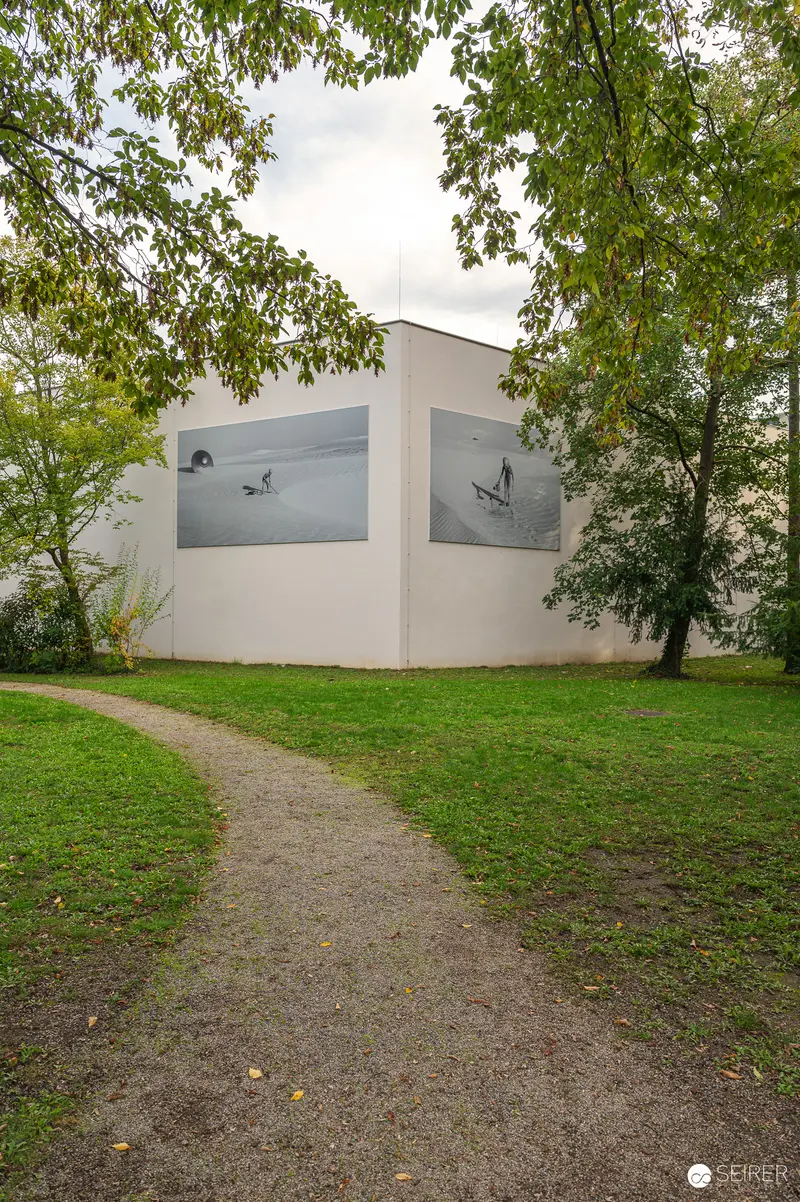 Minimalist White Building Surrounded by Trees on Gravel Pathway