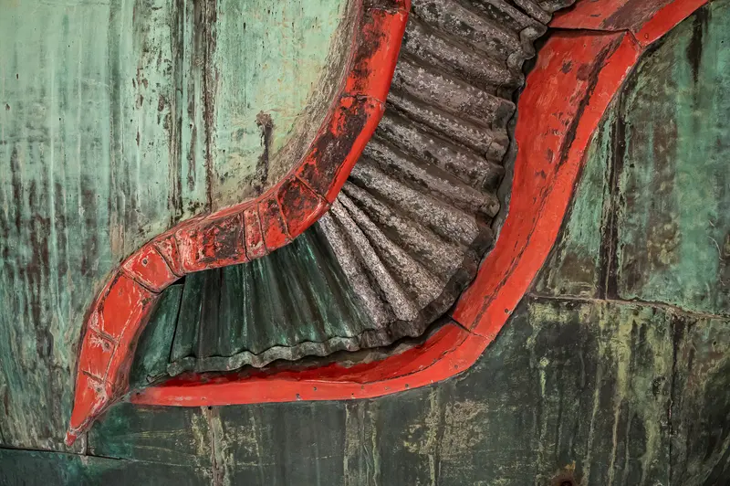 The Wien Museum's 2024 restoration days revealed detailed architectural elements of the Poldi whale sculpture, a 10-meter artwork designed by Maria Benke, originally from the demolished Gasthaus zum Walfisch. The close-up shows vibrant red-painted curved sections contrasting with aged copper sheeting and dark patina, exposing the intricate structural framework beneath. This documentation captures both the craftsmanship of Benke's design and the conservation work required to preserve this unique Viennese cultural artifact.