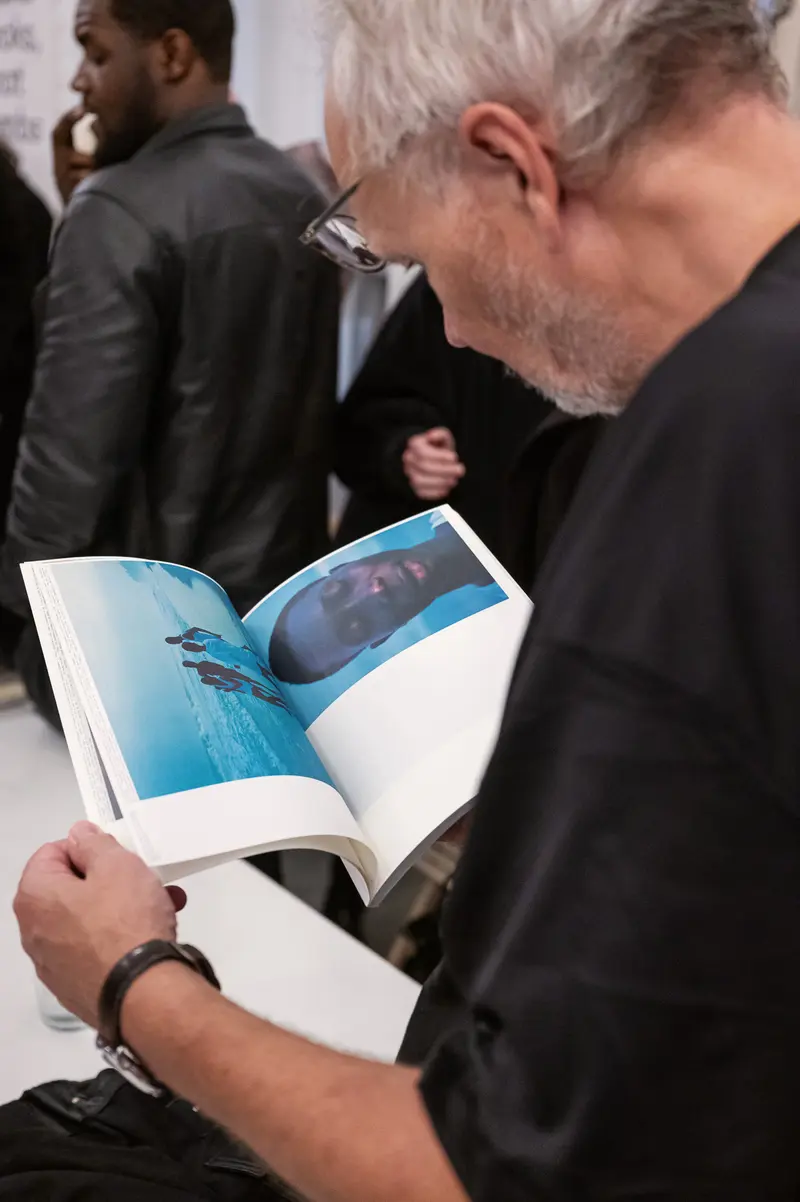 Eric Asamoah Book Presentation: Reader Examining Photobook at Arsenal Wien