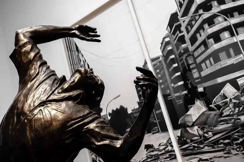 Bronze Sculpture of Dramatic Human Figure Against Urban Architectural Background