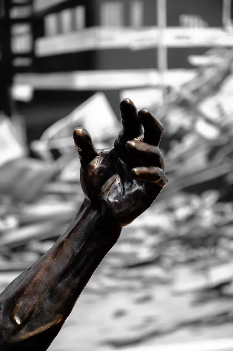 Bronze Sculpture of Clenched Hand in Urban Destruction Landscape