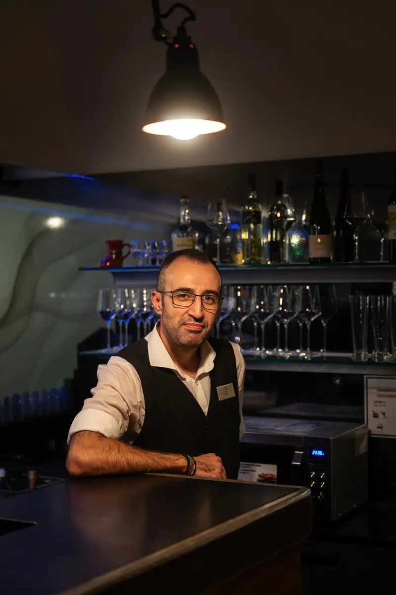 Bartender at Dimly Lit Bar Behind Classic Wooden Counter
