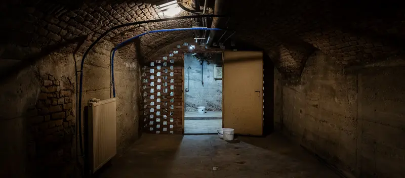 Dimly Lit Underground Corridor with Brick Walls and Open Door