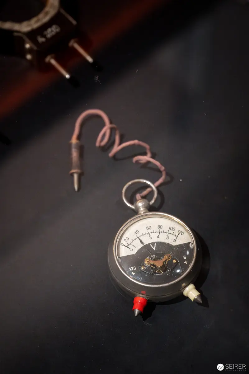 Vintage Analog Voltage Meter with Curved Wire on Dark Background