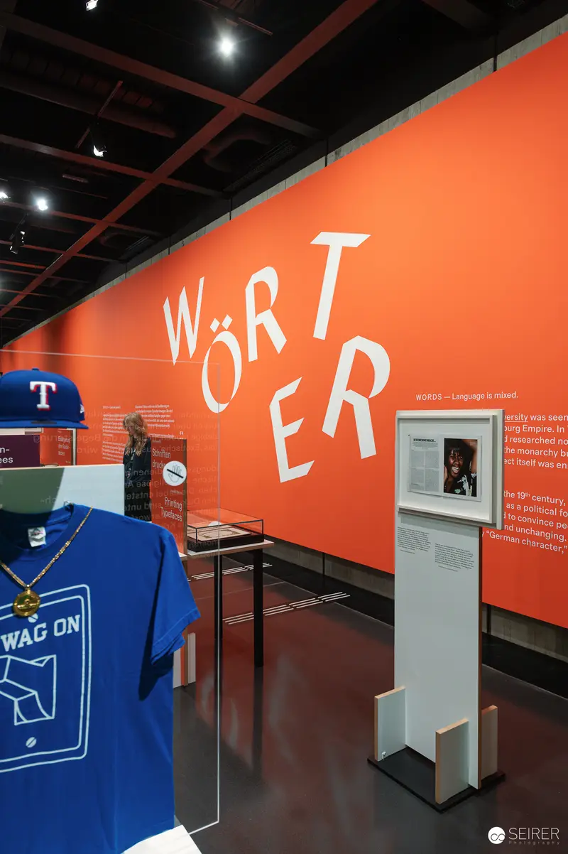 Wien Museum 'MIXED' Ausstellungseröffnung. Orange Wall Display with "WÖRTER" Typography at Wien Museum Mixed Exhibition