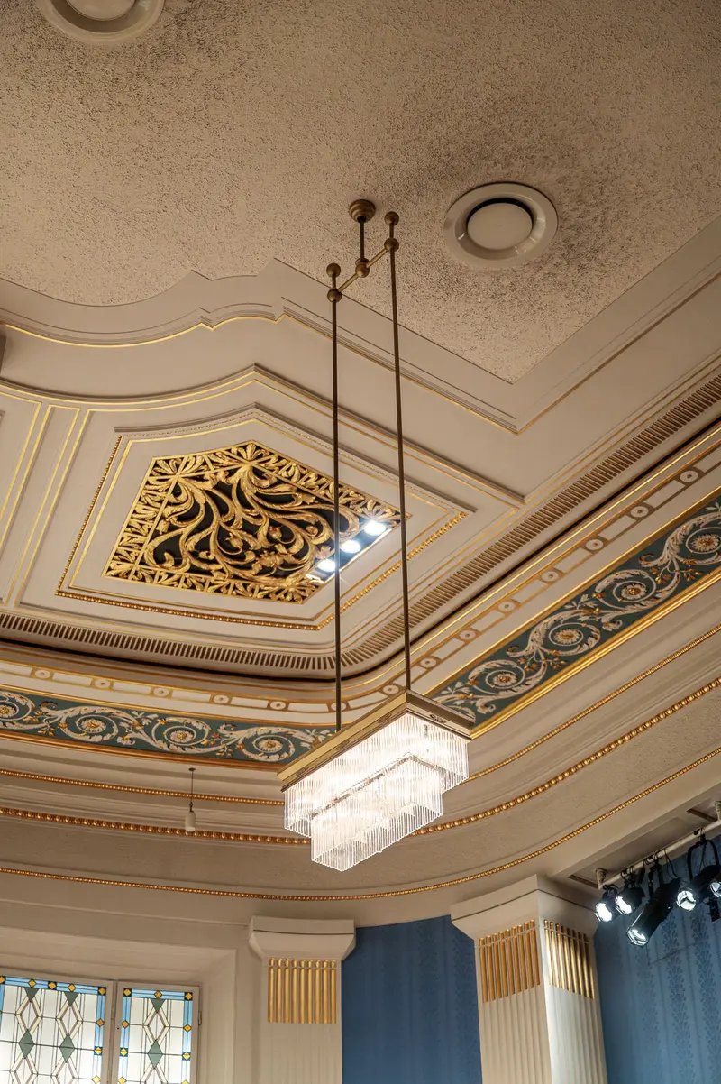 Ornate Concert Hall Ceiling with Decorative Gold Emblem and Chandelier