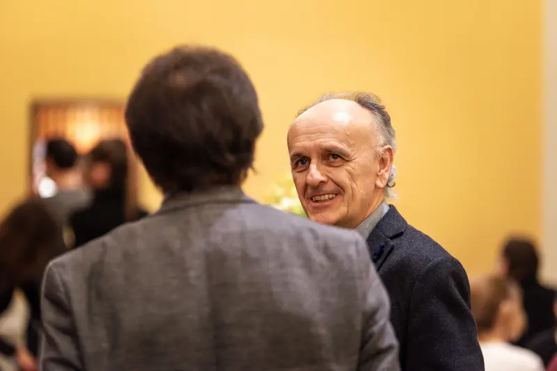 Smiling Older Man in Conversation at TU Orchestra Event in Vienna