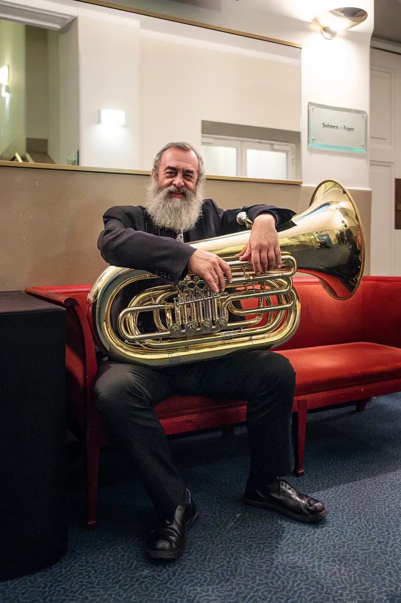 Seasoned Musician Seated with Tuba at TU Orchestra Concert Celebration