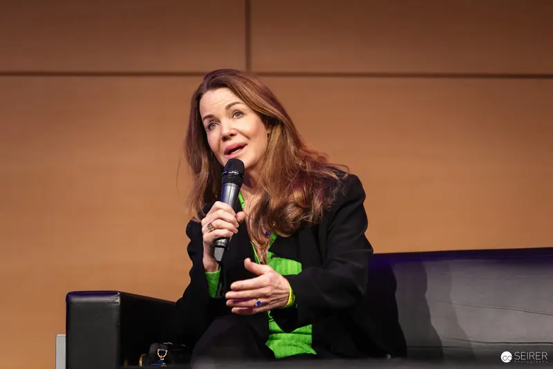 Woman Speaking at Conference with Microphone in Black and Green Outfit