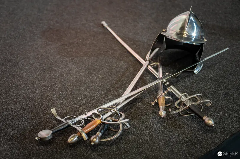 Antique Fencing Rapiers and Decorative Helmet on Dark Background