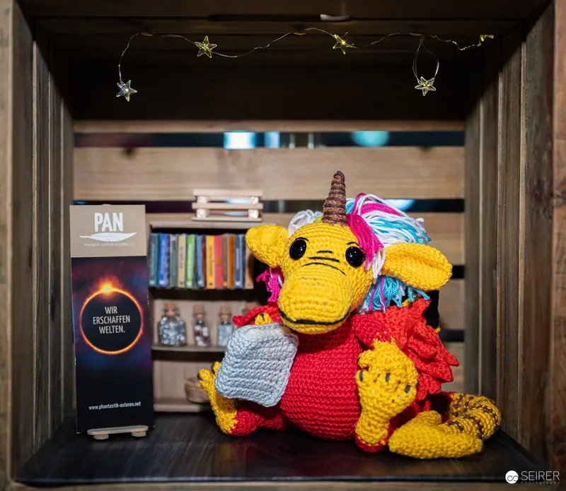 Colorful Crocheted Unicorn Figurine Displayed at Bookshelf with Decorative Stars