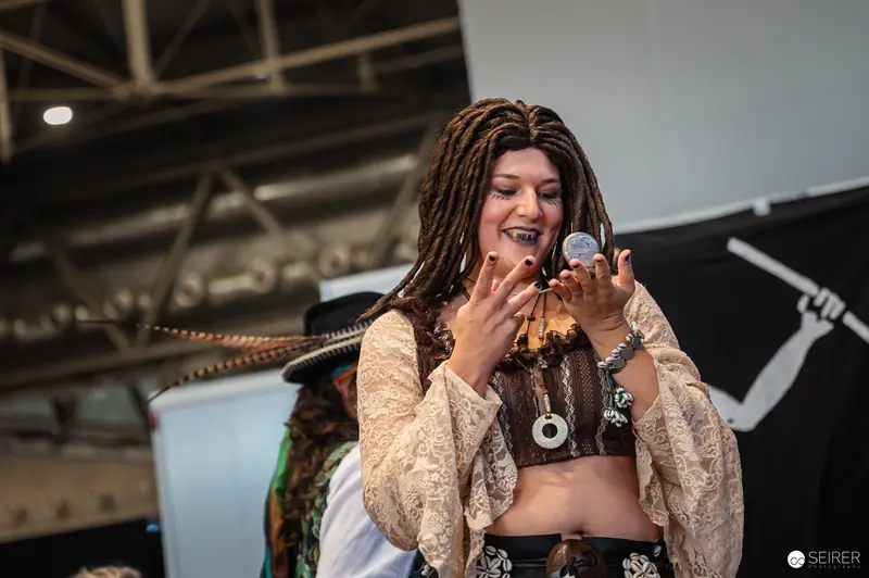 Performer in Bohemian Costume at Vienna ComicCon 2024 Laughing with Prop