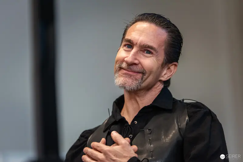 Man in Black Shirt Smiling at Event with Warm Expression