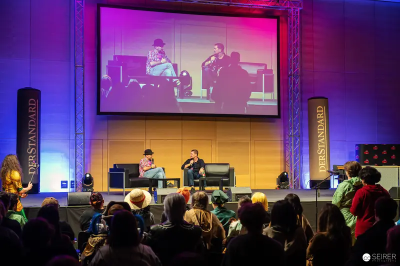 Vienna ComicCon 2024: Panel Discussion Under Vibrant Lighting at Main Stage