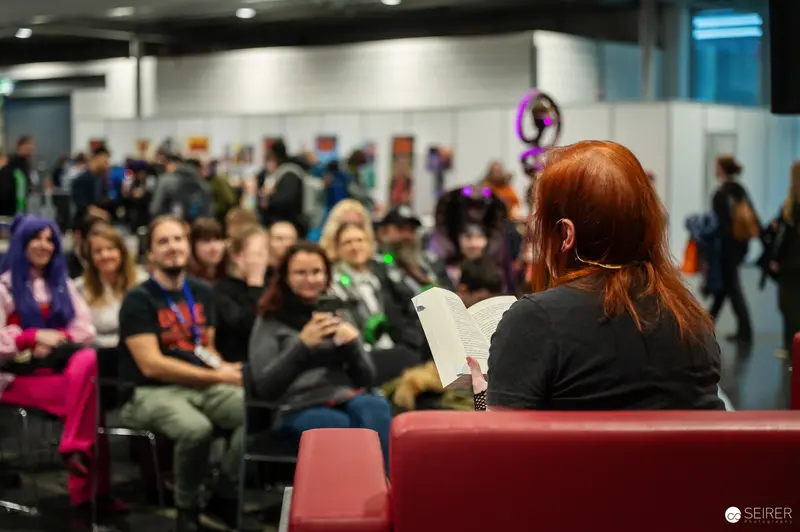 Redheaded Attendee Reading at Vienna ComicCon 2024 Convention Hall