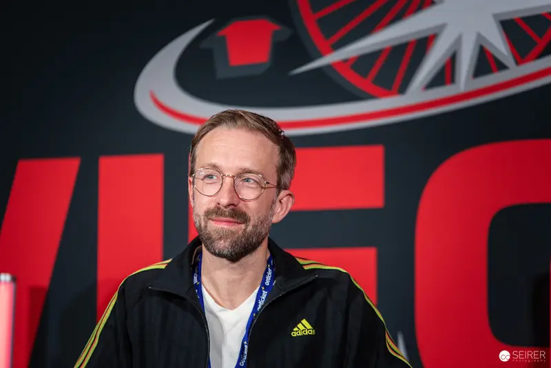 Adidas-Clad Guest at Vienna ComicCon 2024 Against Red Event Backdrop