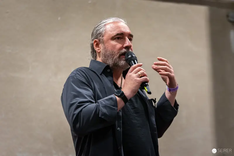 Bearded Speaker Gesturing During Presentation at Vienna ComicCon 2024