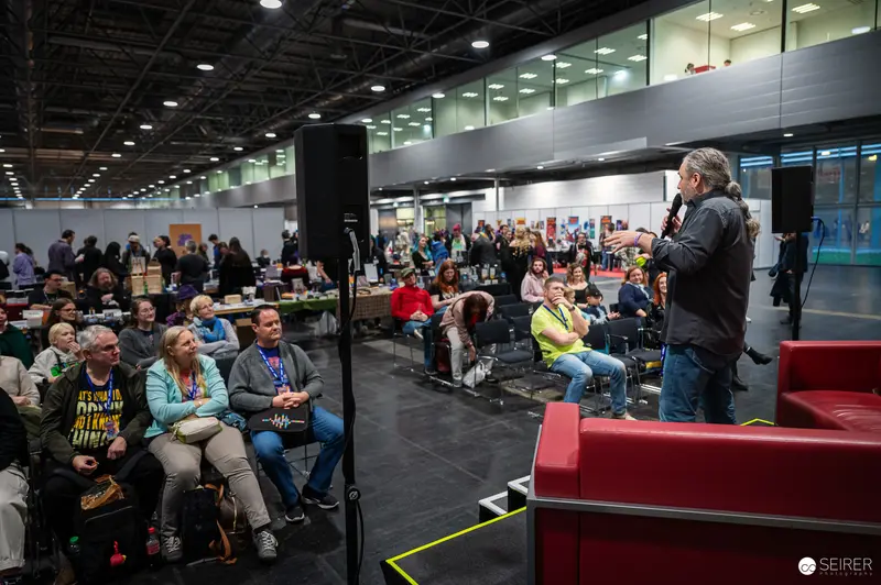 Speaker Addressing Audience at Vienna ComicCon 2024 Convention Hall