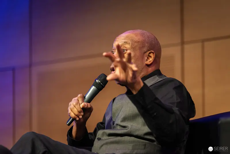 Bald Speaker Gesturing Dramatically During Presentation at Event