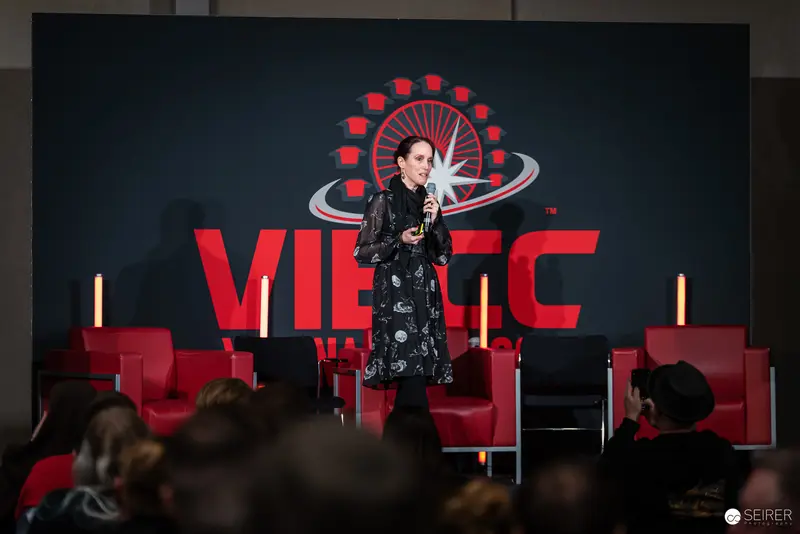 Speaker Presenting at Vienna ComicCon 2024 in Distinctive Black Print Dress