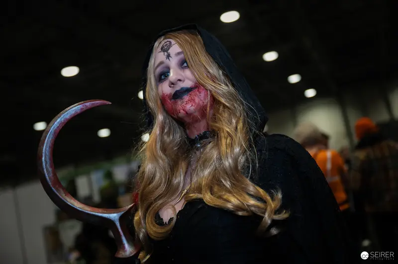 Zombie Cosplayer at Vienna ComicCon 2024 Showcasing Bloody Costume and Prop Scythe
