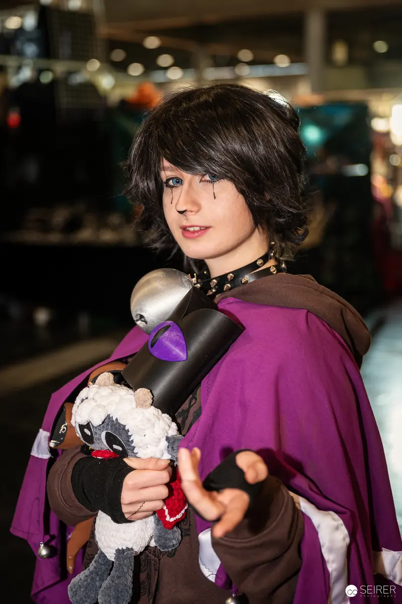 Cosplayer in Purple Cape Posing with Plush at Vienna ComicCon 2024