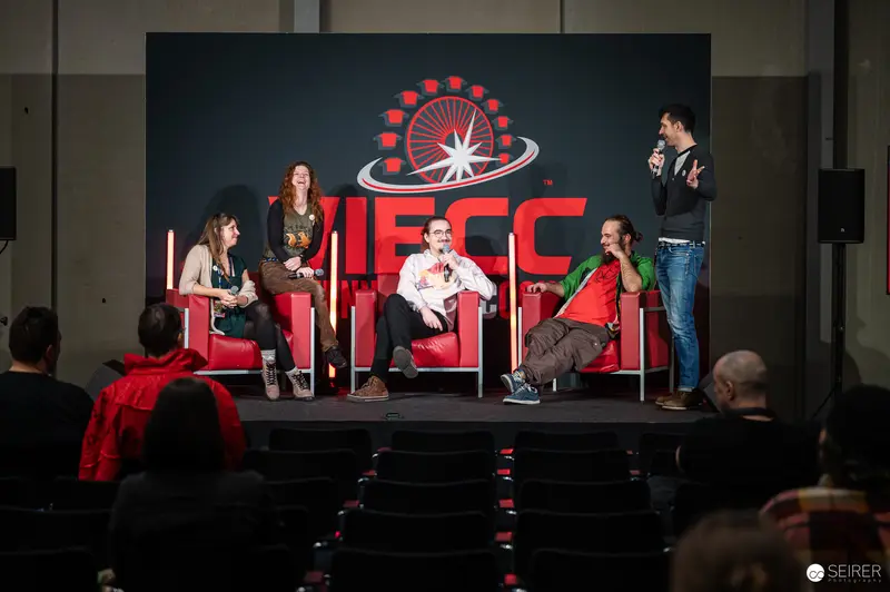 Panel Discussion at Vienna ComicCon 2024, Panelists Seated on Red Chairs