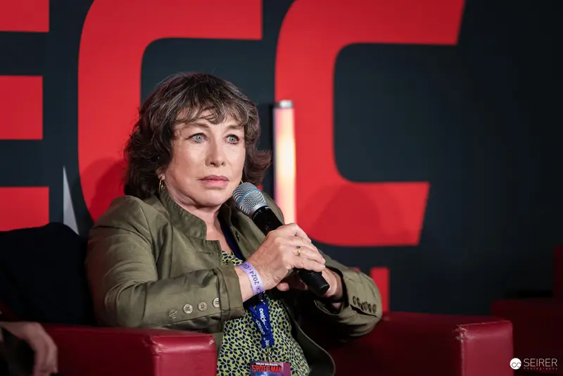 Woman Speaking at Vienna ComicCon 2024 with Microphone and Serious Expression