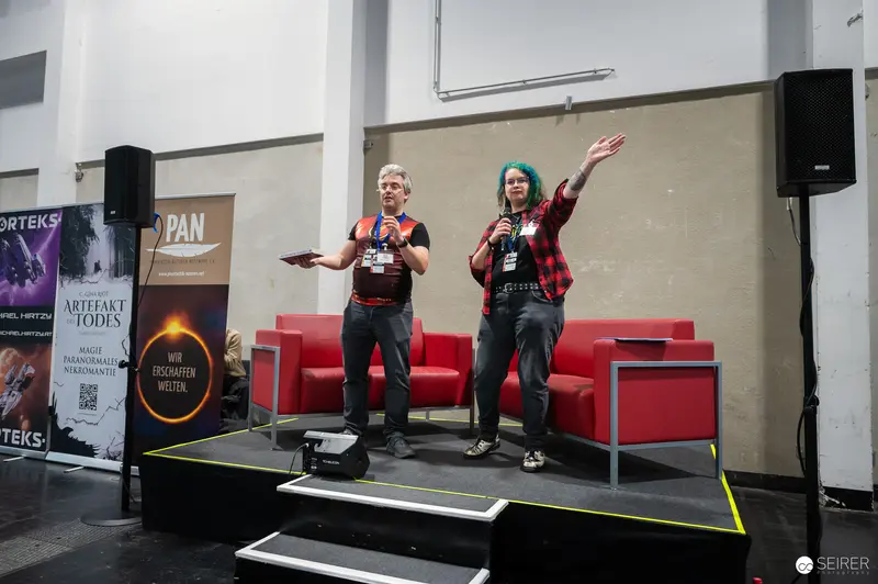 VIECC 2024 Presenters on Stage with Red Seating and Event Banners