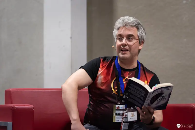 Reader at Vienna ComicCon 2024 Exploring Comic Book with Lanyard and Glasses