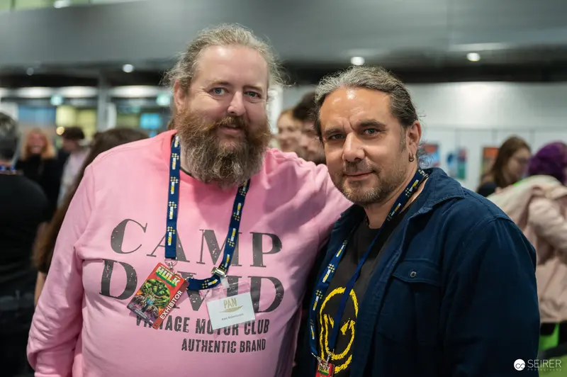 Two Attendees at Vienna ComicCon 2024 Posing in Branded Clothing