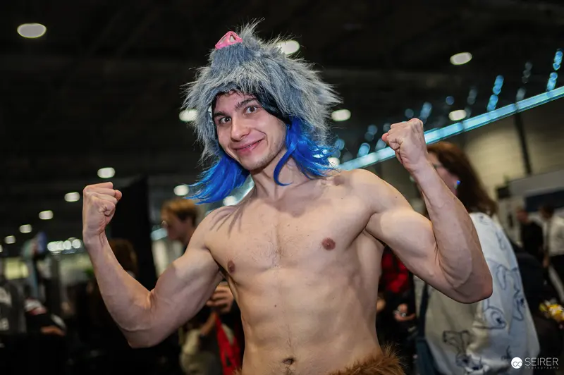Cosplayer in Blue Wig Flexing Muscles at Vienna ComicCon 2024