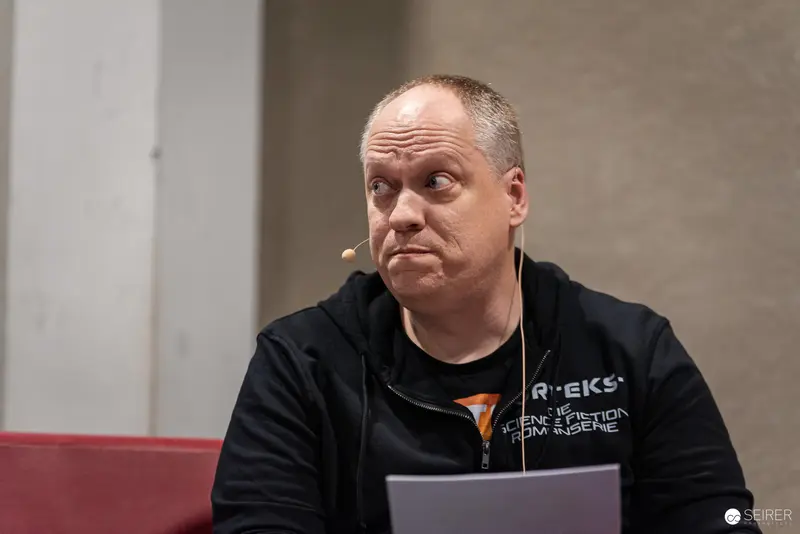 Speaker at Vienna ComicCon 2024 Wearing Black Shirt with Microphone