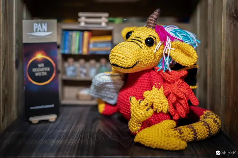 Handcrafted Yellow Knitted Dragon Plush on Wooden Bookshelf