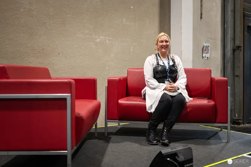 Vienna ComicCon 2024: Attendee in White Coat and Black Vest on Red Sofa