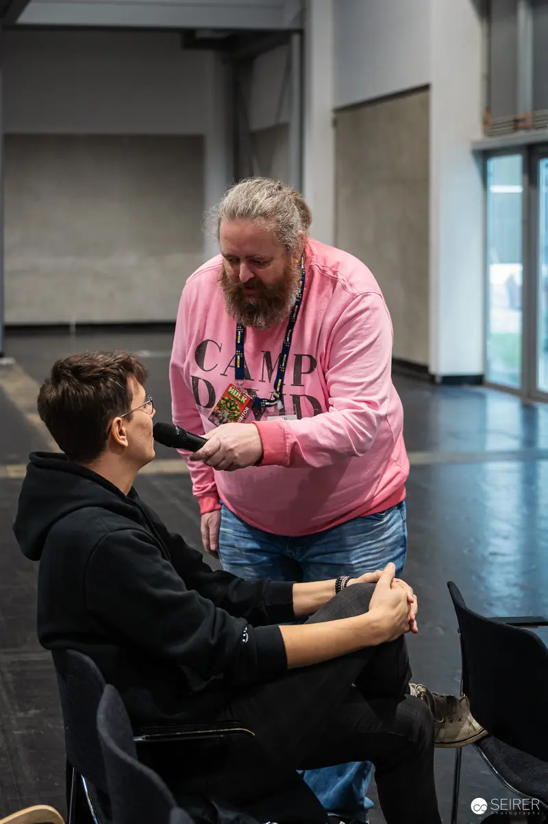 Pink Shirt Tattoo Artist Assisting Person at ComicCon Event