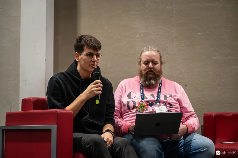 ComicCon Speakers at Vienna Design Event with Microphone and Laptop